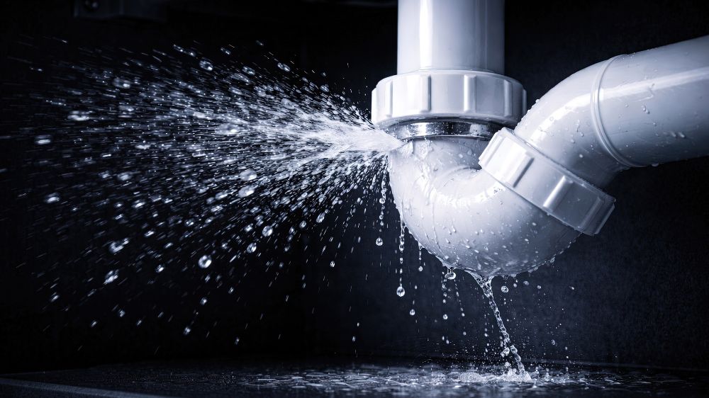 Leaking pipe spraying water, illustrating smart water leak detection and automatic shutoff protection for multifamily properties.
